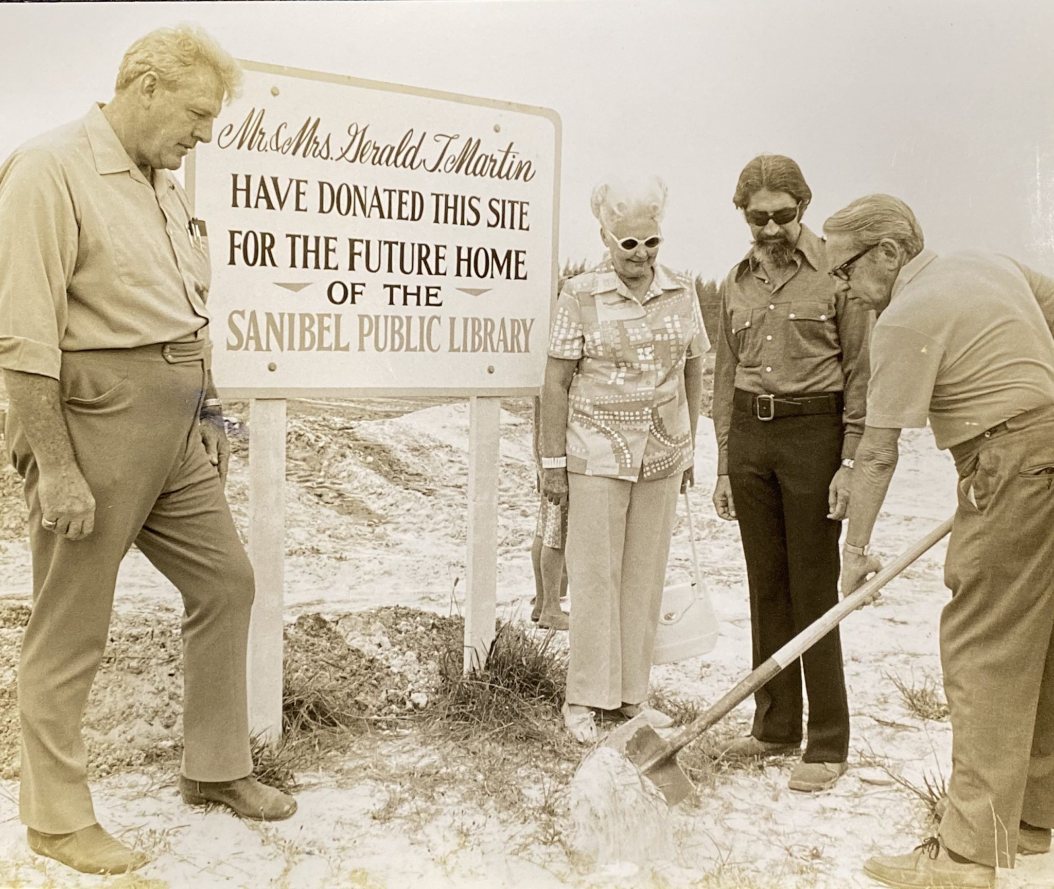 Librarian Mrs. Walter Emmons watches Library Board Pres. Robert Haynie wield shovel at dedication in 1973, with two men from Finder Construction.